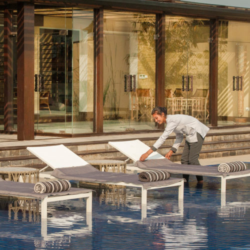 meghauli-serai-maid-making-up-deck-chairs-in-swimming-pool