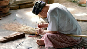 A man using coir to make a broom