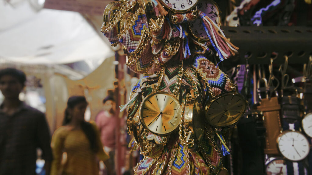 Picture of watches on sale in Colaba street market in Mumbai with a couple visible in the background